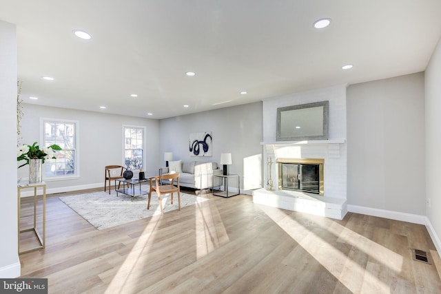 living area featuring recessed lighting, a fireplace, visible vents, baseboards, and light wood-type flooring