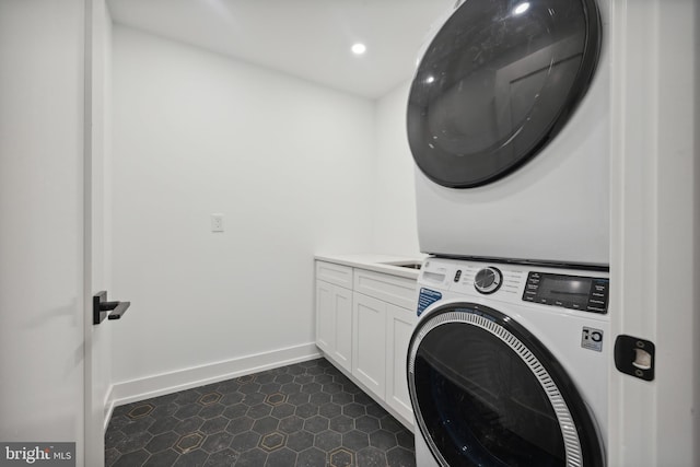 clothes washing area with cabinets and stacked washer and clothes dryer