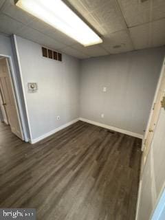 finished basement featuring dark wood-type flooring, a paneled ceiling, visible vents, and baseboards