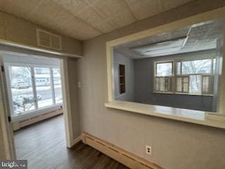 spare room with dark wood-style floors, a baseboard radiator, and visible vents