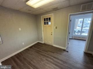 interior space featuring a paneled ceiling, baseboards, visible vents, and dark wood-type flooring