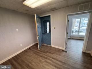 spare room with dark wood-style flooring, visible vents, and baseboards