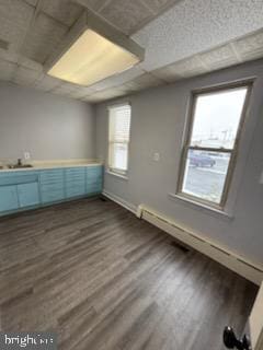 interior space featuring a paneled ceiling, dark wood finished floors, and a sink