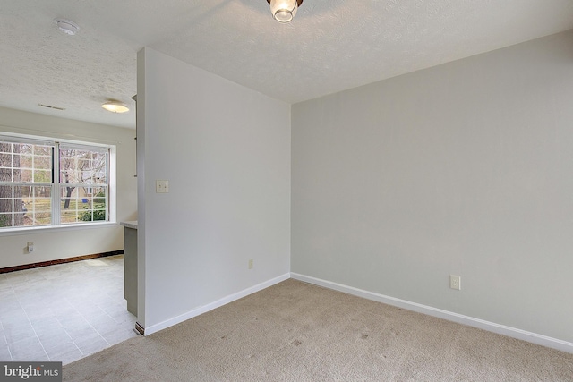 empty room featuring baseboards, a textured ceiling, and light colored carpet