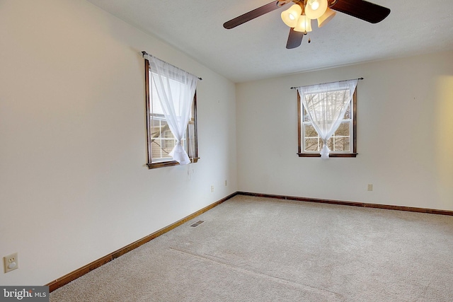 carpeted empty room with a healthy amount of sunlight, visible vents, and baseboards