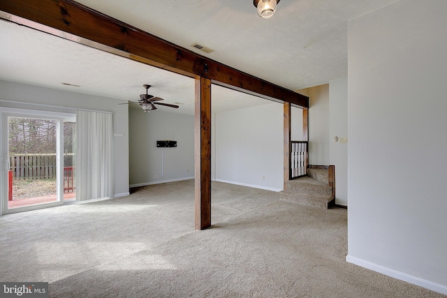 interior space with a textured ceiling, beamed ceiling, visible vents, and light colored carpet