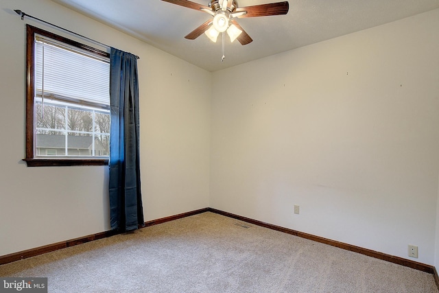 carpeted spare room featuring ceiling fan and baseboards