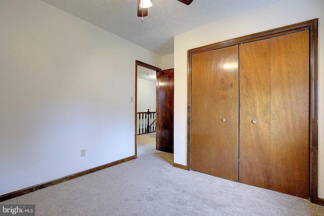 unfurnished bedroom with light carpet, a ceiling fan, baseboards, and a closet