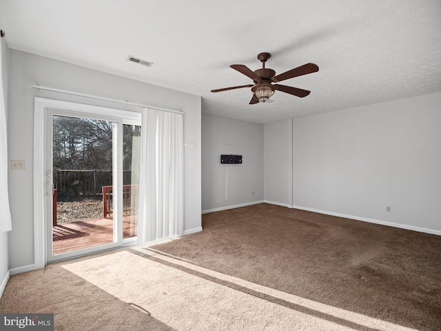 empty room with carpet flooring, a textured ceiling, and baseboards