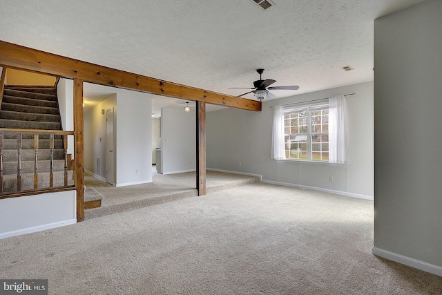 empty room featuring ceiling fan, a textured ceiling, light carpet, baseboards, and stairway