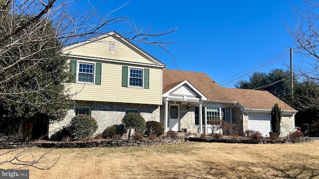 view of front of home featuring a front yard, stone siding, and an attached garage