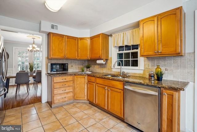 kitchen featuring appliances with stainless steel finishes, brown cabinetry, visible vents, and a sink