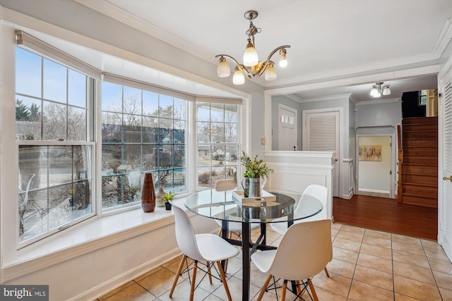 dining area featuring light tile patterned floors, a chandelier, baseboards, ornamental molding, and stairway