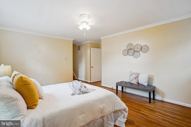 bedroom with crown molding, visible vents, baseboards, and wood finished floors