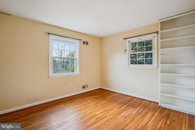 spare room with visible vents, baseboards, and wood finished floors