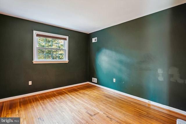 spare room featuring visible vents, baseboards, and wood finished floors