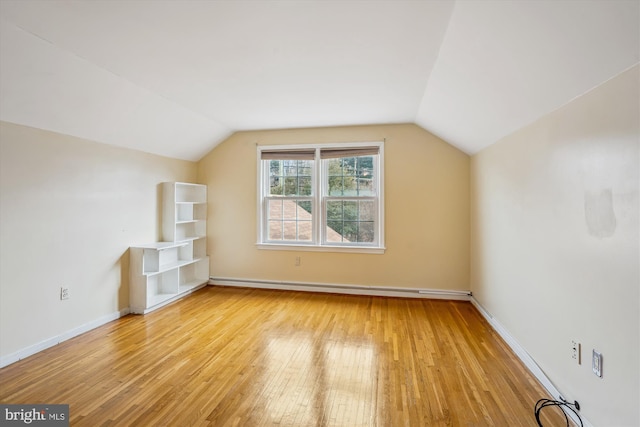 additional living space with vaulted ceiling, light wood-type flooring, a baseboard radiator, and baseboards