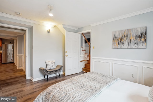 bedroom featuring dark wood-style floors, freestanding refrigerator, wainscoting, and crown molding