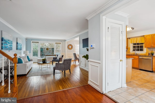 living area featuring a wealth of natural light, a wainscoted wall, and crown molding