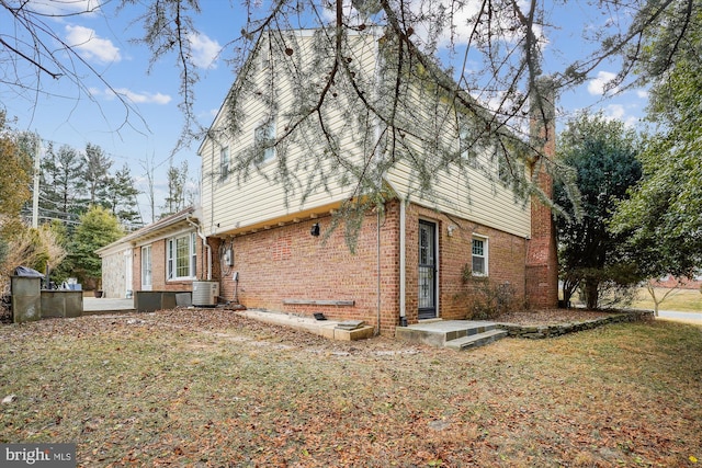 rear view of house with brick siding, a lawn, and central air condition unit