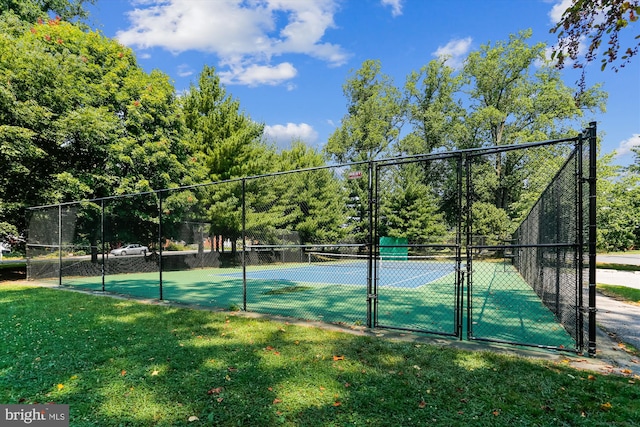 view of tennis court featuring a yard, fence, and a gate