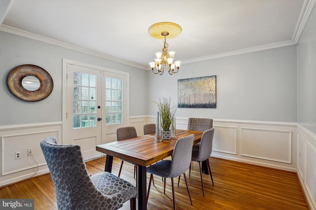 dining area with french doors, wainscoting, wood finished floors, and a notable chandelier