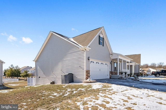 view of snow covered exterior with a garage and covered porch