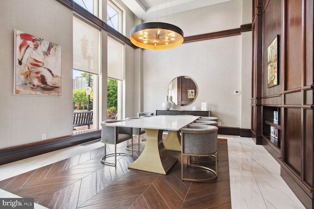 dining area with a chandelier, a towering ceiling, and baseboards