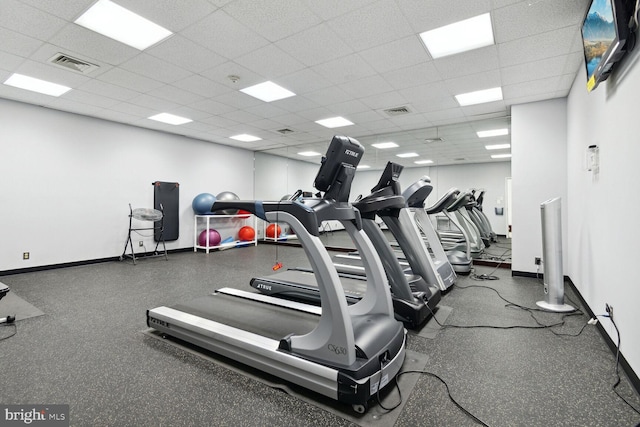 gym featuring a paneled ceiling, visible vents, and baseboards