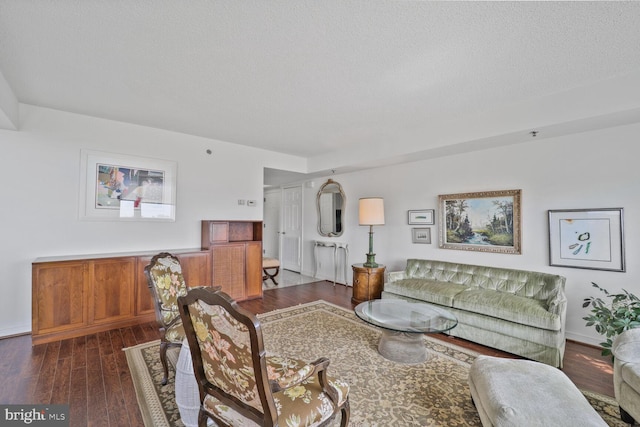 living room with dark wood-style floors, a textured ceiling, and baseboards