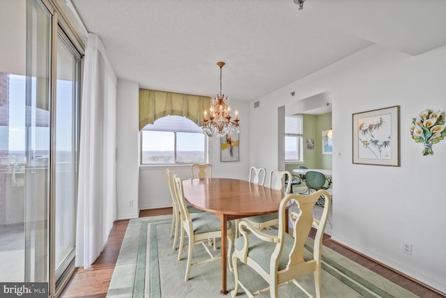 dining room featuring a chandelier, light wood finished floors, a textured ceiling, and baseboards