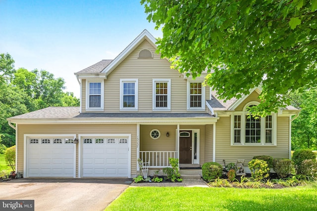 traditional-style home featuring a porch, roof with shingles, a front yard, and aphalt driveway