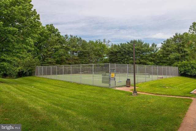 view of tennis court featuring fence and a lawn