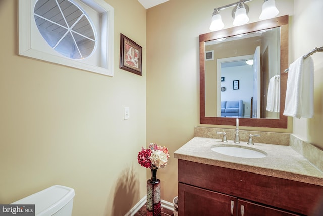 half bath featuring toilet, visible vents, and vanity