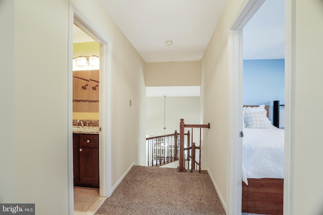 corridor featuring light carpet, baseboards, and an upstairs landing