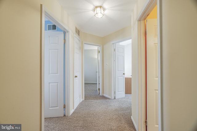 hall featuring carpet, visible vents, and baseboards