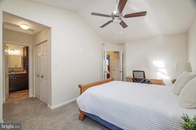 bedroom with lofted ceiling, light colored carpet, a sink, ensuite bath, and baseboards