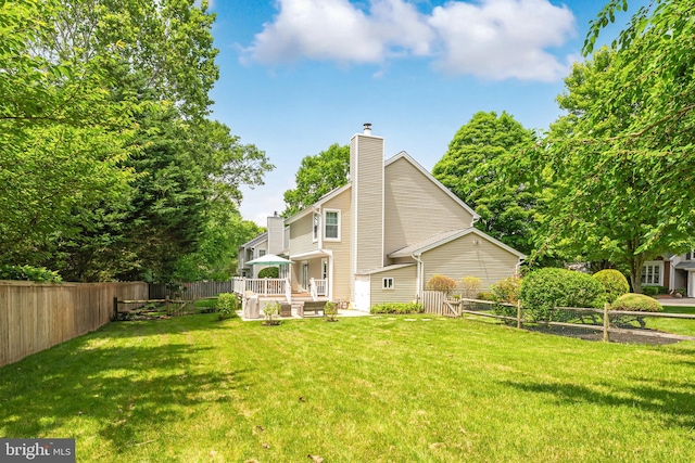 back of property featuring a chimney, a fenced backyard, a yard, and a deck