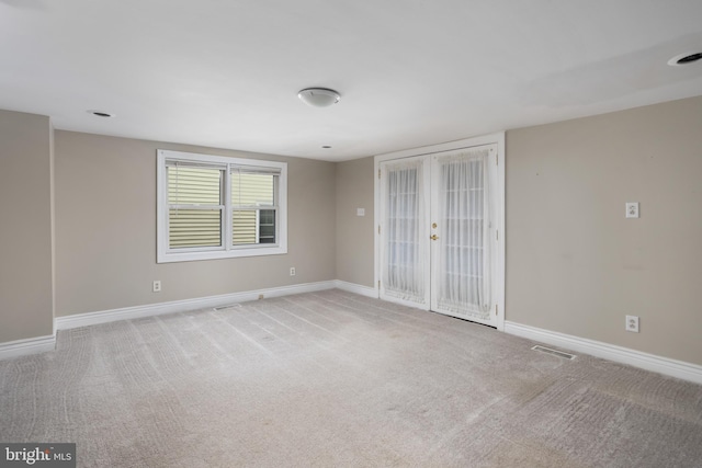 empty room featuring french doors and light carpet