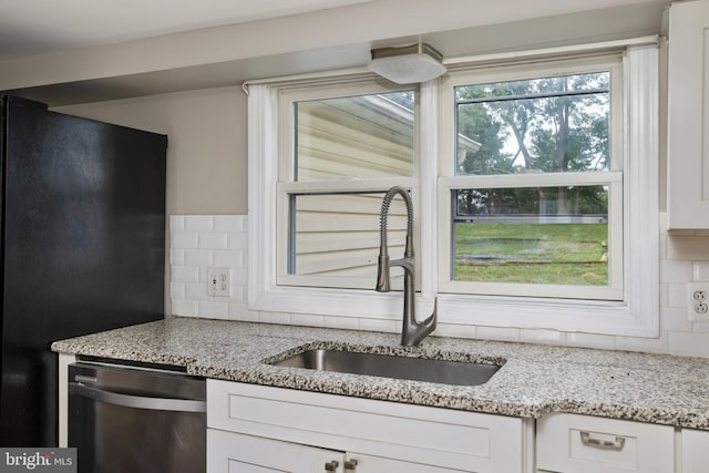 kitchen with white cabinetry, stainless steel dishwasher, black fridge, and sink