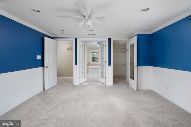 unfurnished bedroom with french doors, ornamental molding, light colored carpet, ceiling fan, and a closet