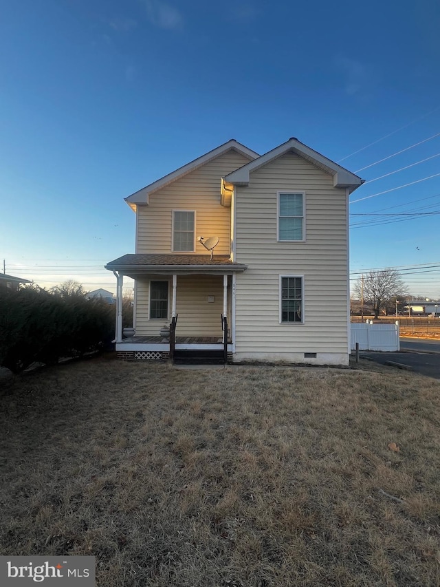 rear view of property featuring a porch and a yard