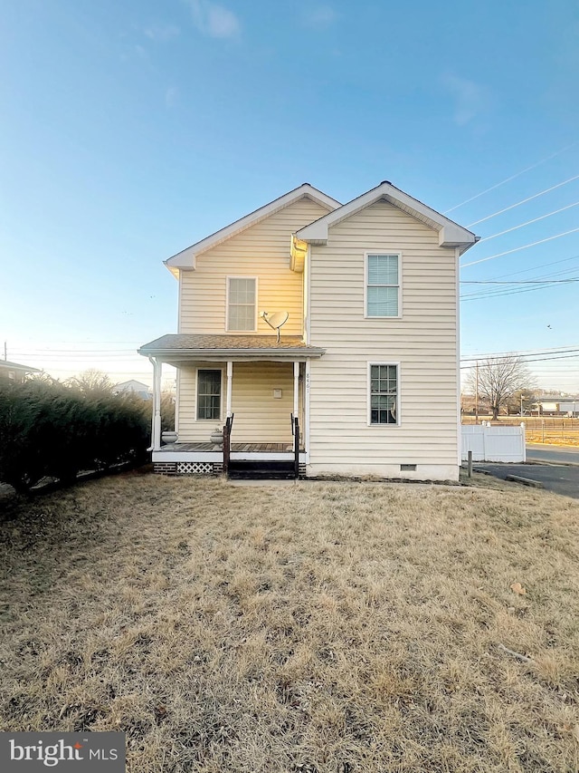 back of property featuring a yard and covered porch