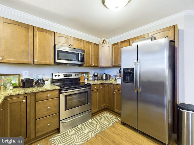 kitchen with appliances with stainless steel finishes, light stone counters, light hardwood / wood-style flooring, and ornamental molding