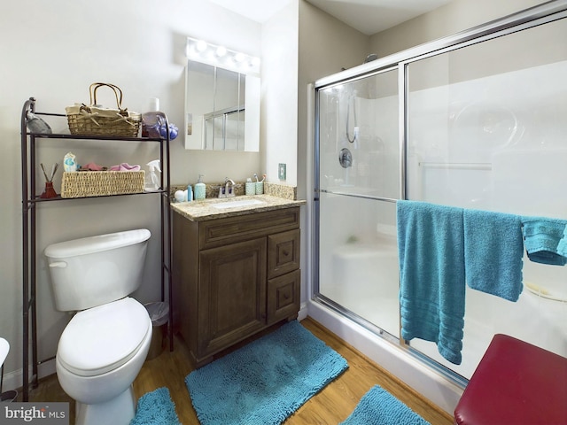 bathroom featuring toilet, wood-type flooring, vanity, and a shower with door