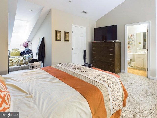 carpeted bedroom with vaulted ceiling and ensuite bathroom