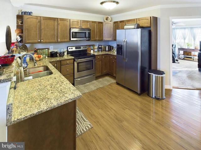 kitchen featuring light hardwood / wood-style flooring, sink, light stone counters, appliances with stainless steel finishes, and crown molding