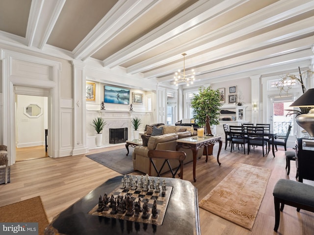 living room with a high end fireplace, beamed ceiling, crown molding, and a notable chandelier