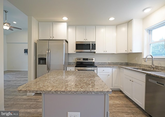 kitchen featuring stainless steel appliances, a sink, white cabinets, and light stone countertops