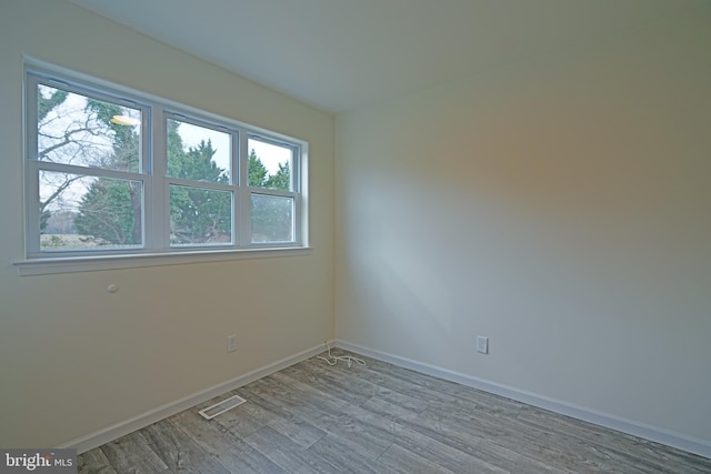 empty room with baseboards, visible vents, and wood finished floors